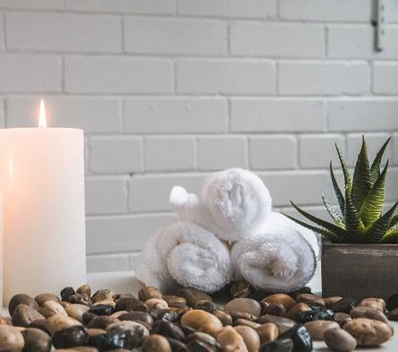 Candle and 3 small rolled towels in spa setting