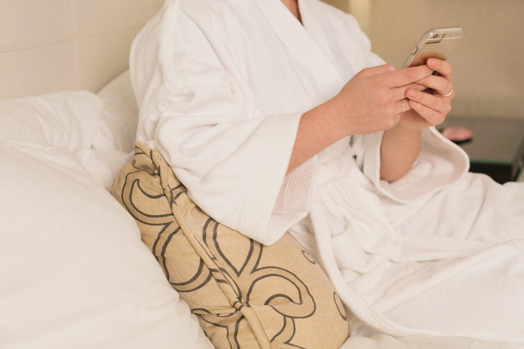 Woman in robes laying back looking at phone